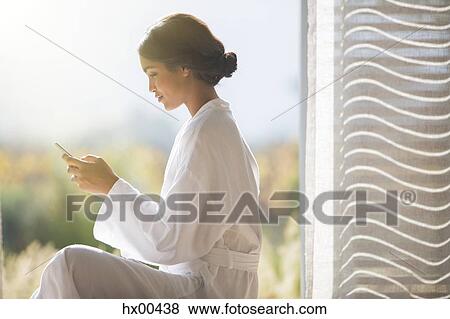 Woman in bathrobe texting with cell phone in sunny doorway View Large Photo Image Stock Photo - Woman in bathrobe texting with cell phone in sunny doorway. Fotosearch