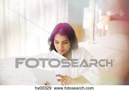 Woman in bathrobe using digital tablet on bed View Large Photo Image Stock Photo - Woman in bathrobe using digital tablet on bed. Fotosearch
