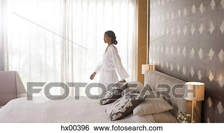 Stock Photograph - Woman in bathrobe walking in bedroom. Fotosearch