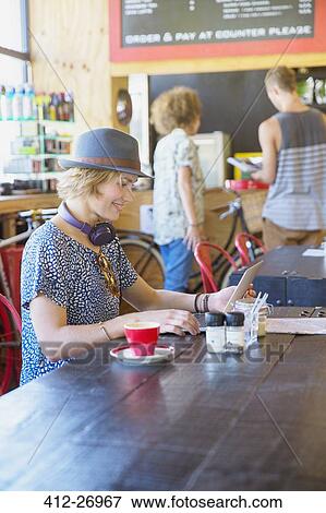 Stock Photo - Woman in hat using digital tablet at cafe. Fotosearch