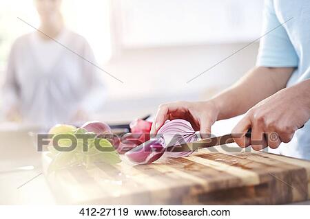 Stock Photo - Woman slicing red onion on cutting board in kitchen. Fotosearch
