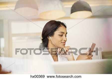 Stock Photo - Woman with headphones listening to music on mp3 player. Fotosearch