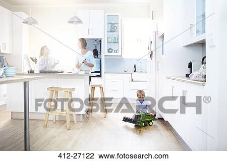 Women cooking in kitchen while boy plays with toy tractor on floor View Large Photo Image Stock Image - Women cooking in kitchen while boy plays with toy tractor on floor. Fotosearch