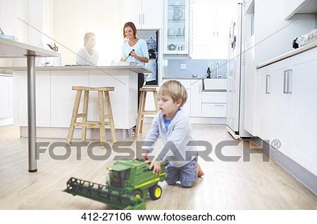 Women cooking in kitchen while boy plays with toy tractor on floor View Large Photo Image Stock Photograph - Women cooking in kitchen while boy plays with toy tractor on floor. Fotosearch