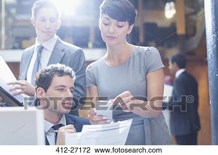 Business people looking at cell phone in office View Large Photo Image Stock Image - Business people looking at cell phone in office. Fotosearch