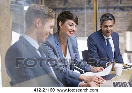 Stock Image - Business people reviewing paperwork in meeting. Fotosearch