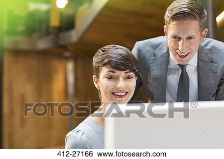 Stock Photograph - Businessman and businesswoman using computer in office. Fotosearch