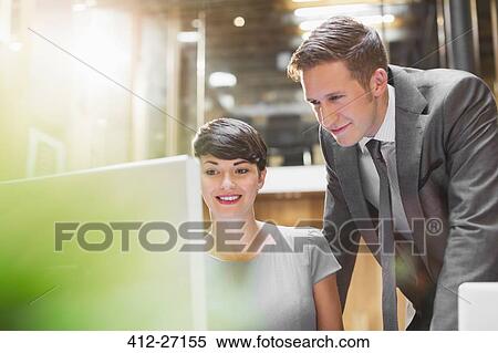 Stock Photography - Businessman and businesswoman using computer in office. Fotosearch