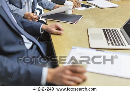 Stock Photo - Businessman drinking coffee at laptop in meeting. Fotosearch