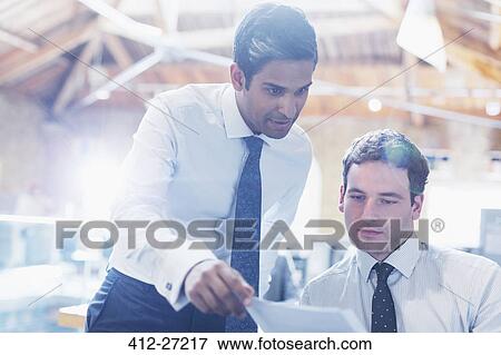 Businessmen reading paperwork in office View Large Photo Image Stock Photo - Businessmen reading paperwork in office. Fotosearch