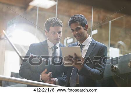 Stock Photograph - Businessmen using digital tablet in office. Fotosearch
