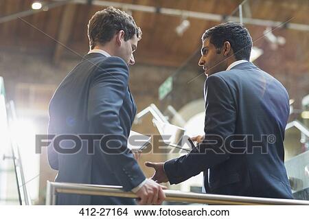Businessmen with digital tablet talking in office View Large Photo Image Picture - Businessmen with digital tablet talking in office. Fotosearch