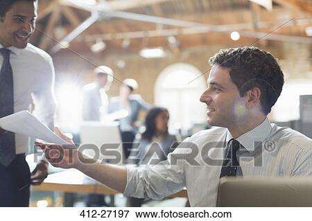 Stock Photo - Businessmen with paperwork in office. Fotosearch