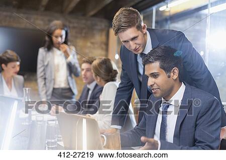 Stock Photo - Businessmen working at laptop in conference room meeting. Fotosearch
