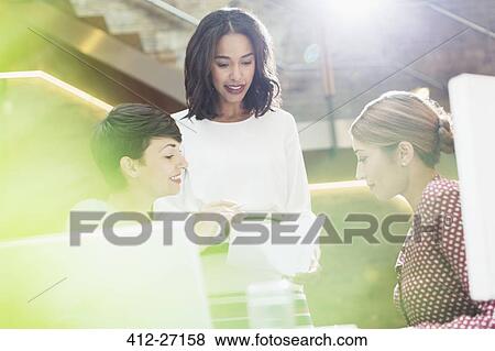 Stock Photo - Businesswomen reviewing paperwork in office. Fotosearch