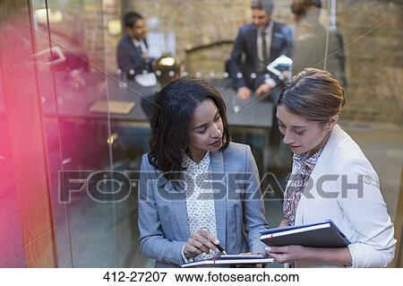 Businesswomen talking outside conference room meeting View Large Photo Image Stock Photo - Businesswomen talking outside conference room meeting. Fotosearch