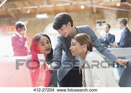 Picture - Businesswomen texting with cell phone in office. Fotosearch