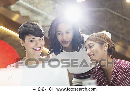 Stock Image - Businesswomen using laptop in office. Fotosearch