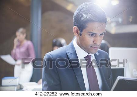 Focused businessman working at laptop in office View Large Photo Image Stock Image - Focused businessman working at laptop in office. Fotosearch