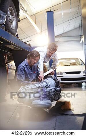 Mechanic and customer examining engine part in auto repair shop View Large Photo Image Stock Photography - Mechanic and customer examining engine part in auto repair shop. Fotosearch