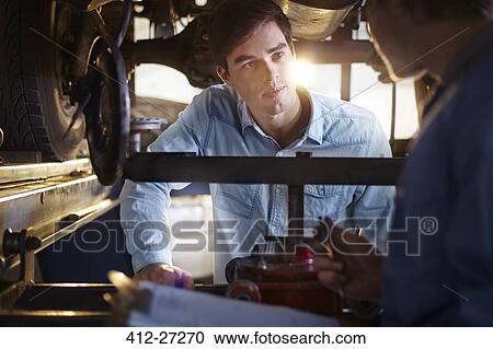 Mechanic and customer talking under car in auto repair shop View Large Photo Image Stock Image - Mechanic and customer talking under car in auto repair shop. Fotosearch