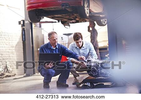 Mechanic and customer with laptop examining engine in auto repair shop View Large Photo Image Stock Image - Mechanic and customer with laptop examining engine in auto repair shop. Fotosearch