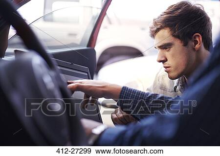 Stock Photo - Mechanic and customer with laptop inside car. Fotosearch