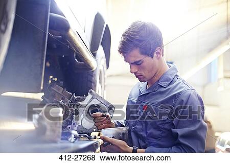 Stock Photo - Mechanic examining part in auto repair shop. Fotosearch