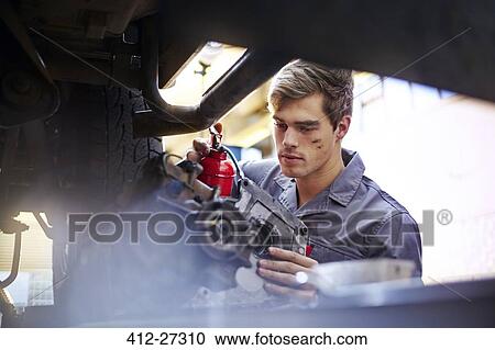 Mechanic oiling part in auto repair shop View Large Photo Image Stock Image - Mechanic oiling part in auto repair shop. Fotosearch