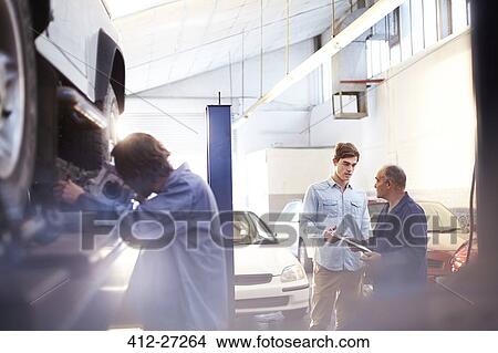 Mechanic speaking with customer in auto repair shop View Large Photo Image Picture - Mechanic speaking with customer in auto repair shop. Fotosearch