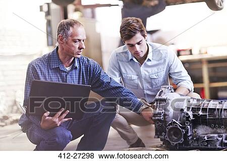 Mechanic with laptop and customer examining engine in auto repair shop View Large Photo Image Stock Photo - Mechanic with laptop and customer examining engine in auto repair shop. Fotosearch