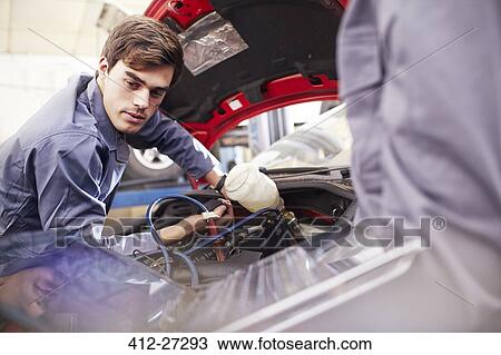 Stock Image - Mechanic working on car engine in auto repair shop. Fotosearch