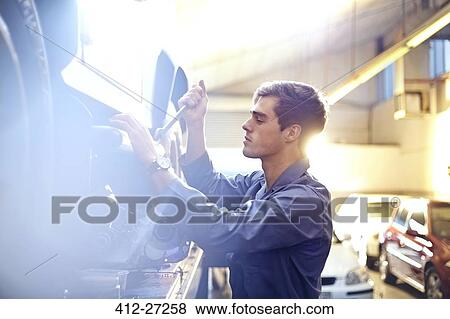 Stock Photo - Mechanic working on car in auto repair shop. Fotosearch