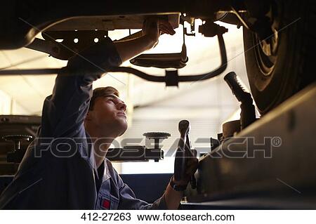 Stock Image - Mechanic working under car in auto repair shop. Fotosearch