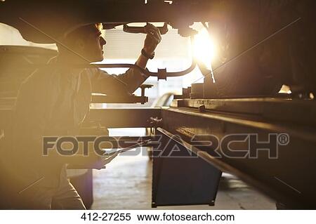 Mechanic working under car View Large Photo Image Stock Photography - Mechanic working under car. Fotosearch