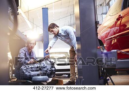 Mechanics discussing engine part in auto repair shop View Large Photo Image Stock Photo - Mechanics discussing engine part in auto repair shop. Fotosearch