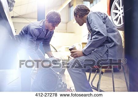 Stock Photo - Mechanics examining engine part in auto repair shop. Fotosearch