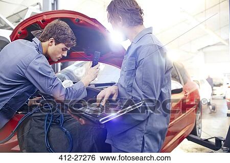 Mechanics with laptop working on car engine in auto repair shop View Large Photo Image Stock Photograph - Mechanics with laptop working on car engine in auto repair shop. Fotosearch