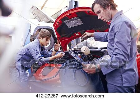 Mechanics working on engine in auto repair shop View Large Photo Image Stock Photo - Mechanics working on engine in auto repair shop. Fotosearch