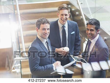 Stock Photo - Portrait confident businessmen with coffee and digital tablet on stairs. Fotosearch