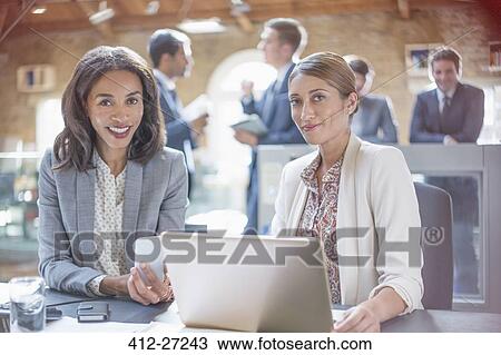 Stock Image - Portrait confident businesswomen working at laptop in office. Fotosearch