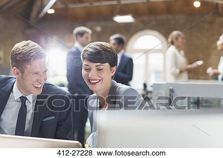 Smiling business people working at laptop in office View Large Photo Image Stock Photo - Smiling business people working at laptop in office. Fotosearch