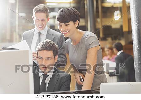 Stock Photograph - Smiling business people working at computer in office. Fotosearch