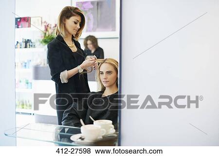 Stock Photo - Hairdresser curling customer’s hair in salon. Fotosearch