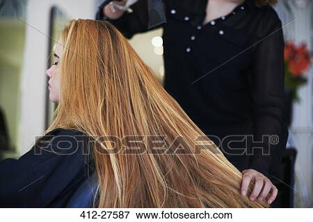 Stock Photo - Hairdresser drying customer’s long hair in salon. Fotosearch