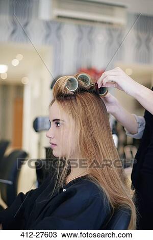 Stock Image - Hairdresser rolling customer’s hair in curlers in salon. Fotosearch