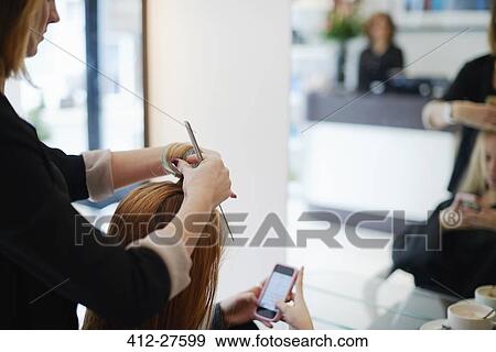 Stock Photo - Hairdresser rolling customer’s hair in rollers in salon. Fotosearch
