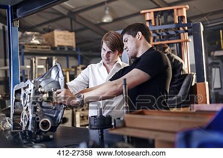 Mechanic and customer examining part in auto repair shop View Large Photo Image Stock Photo - Mechanic and customer examining part in auto repair shop. Fotosearch