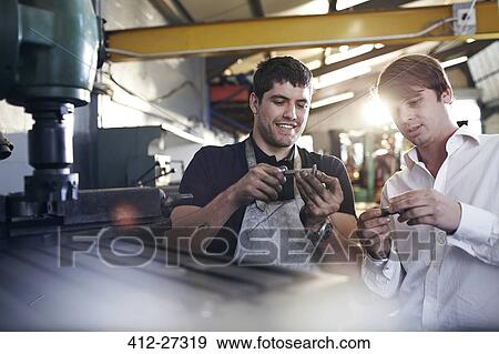 Stock Photo - Mechanic and customer examining parts in auto repair shop. Fotosearch