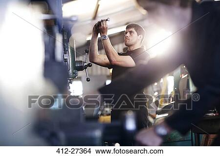 Mechanic examining part in auto repair shop View Large Photo Image Picture - Mechanic examining part in auto repair shop. Fotosearch